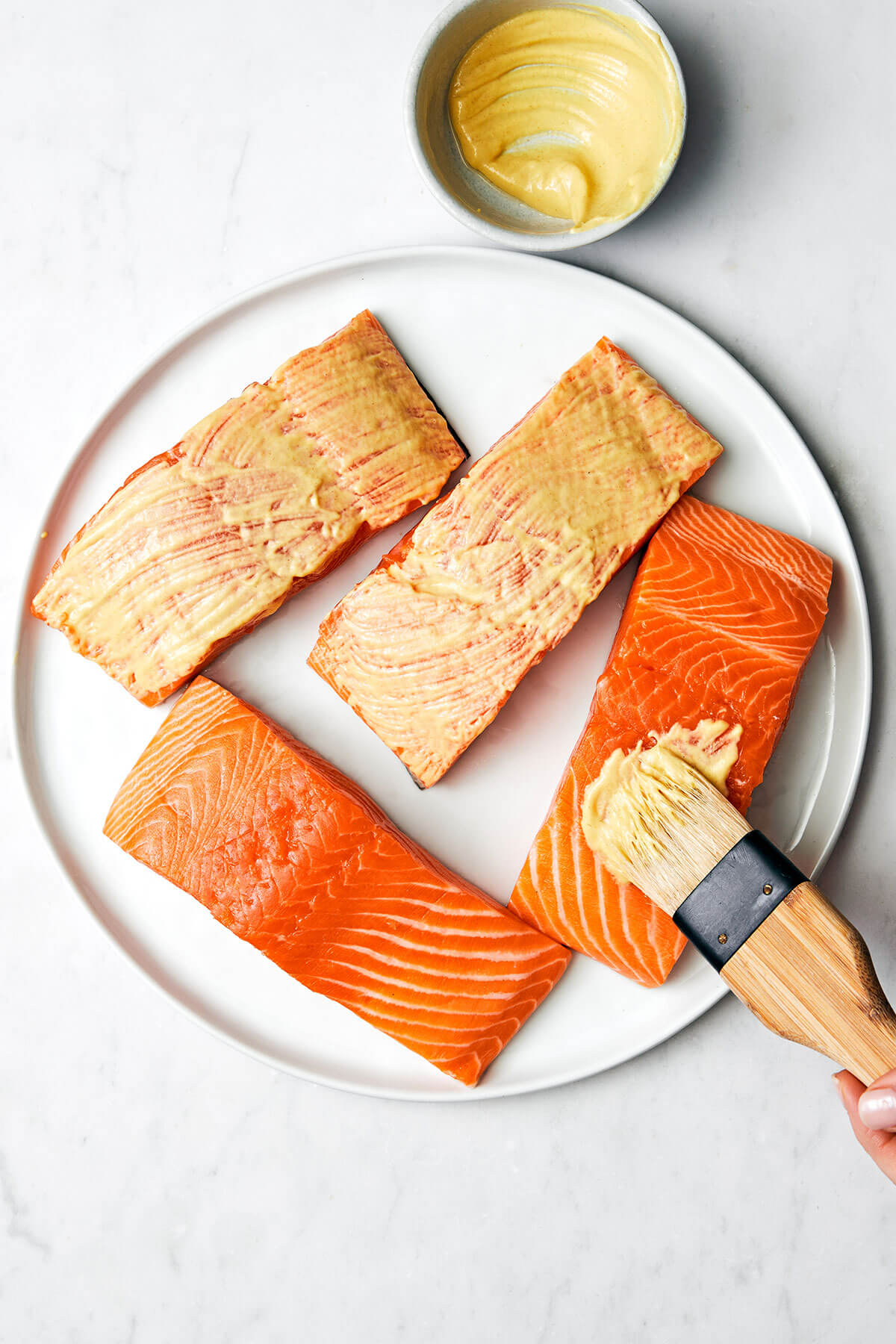 Brushing Dijon mustard on salmon filet.