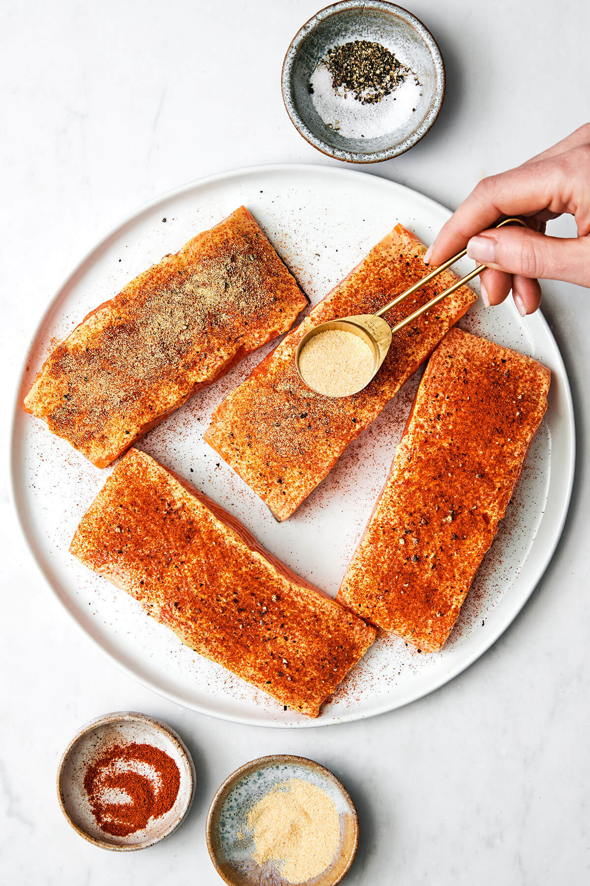 Adding seasoning to salmon filets.