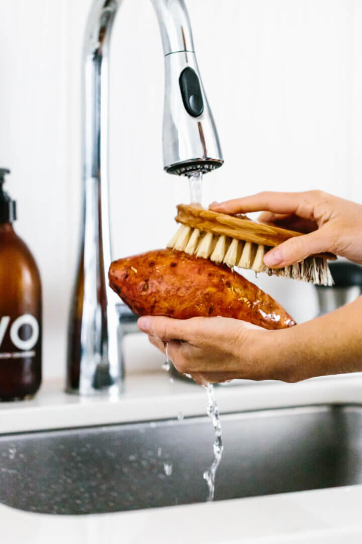 Cleaning a sweet potato with a brush