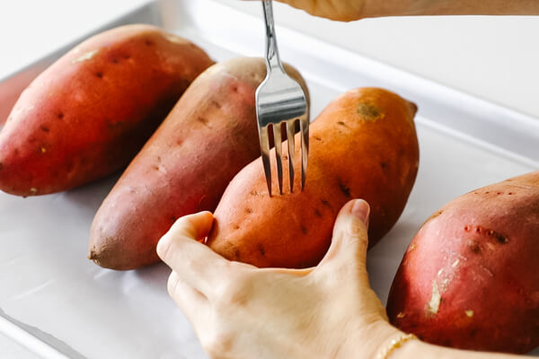 Poking the sweet potato with a fork.