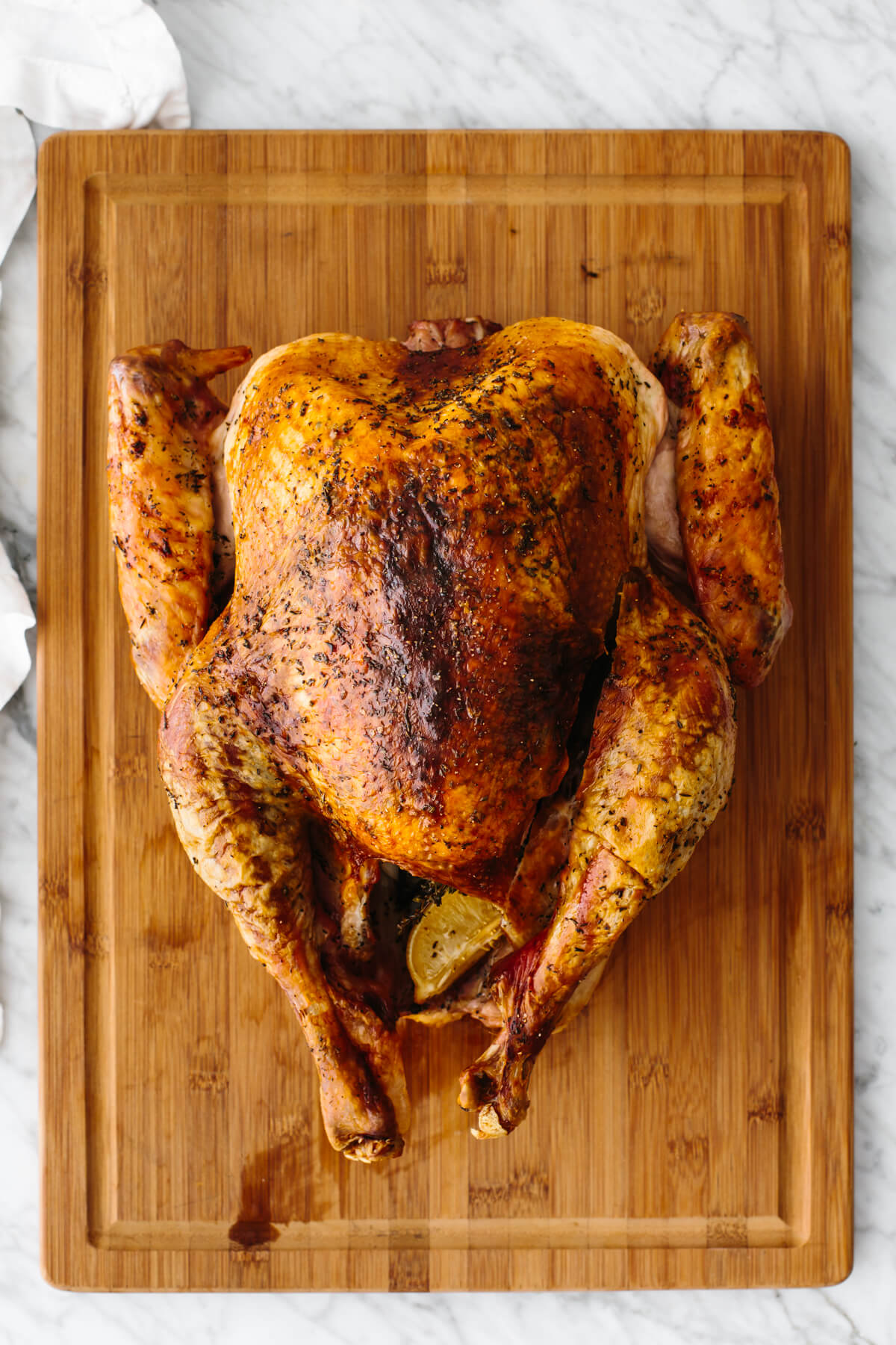 Roasted turkey resting on a wooden board before carving.