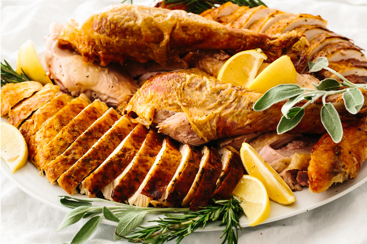 A plate of carved turkey with sage and lemons.