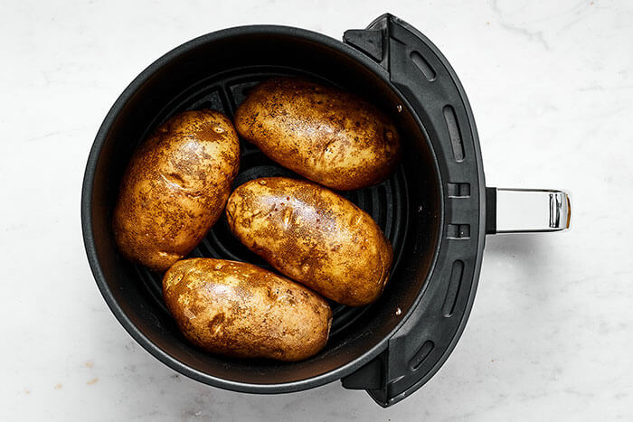 Air fryer basket with potatoes in it