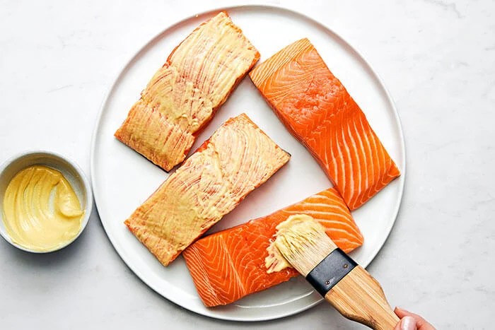 Adding mustard to salmon.