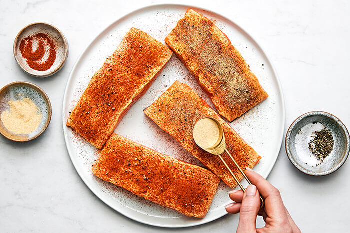 Sprinkling seasoning to salmon filets.
