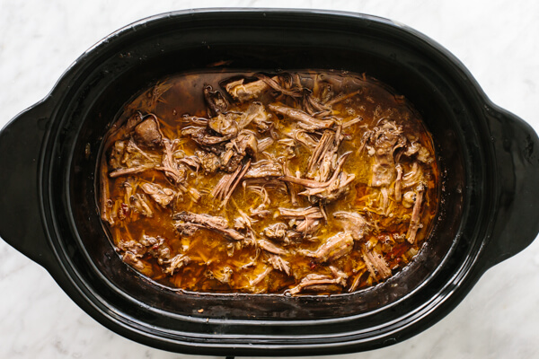 Mixing beef barbacoa in a slow cooker.