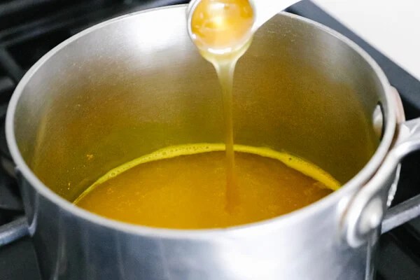 Pouring honey into the pot with turmeric tea.
