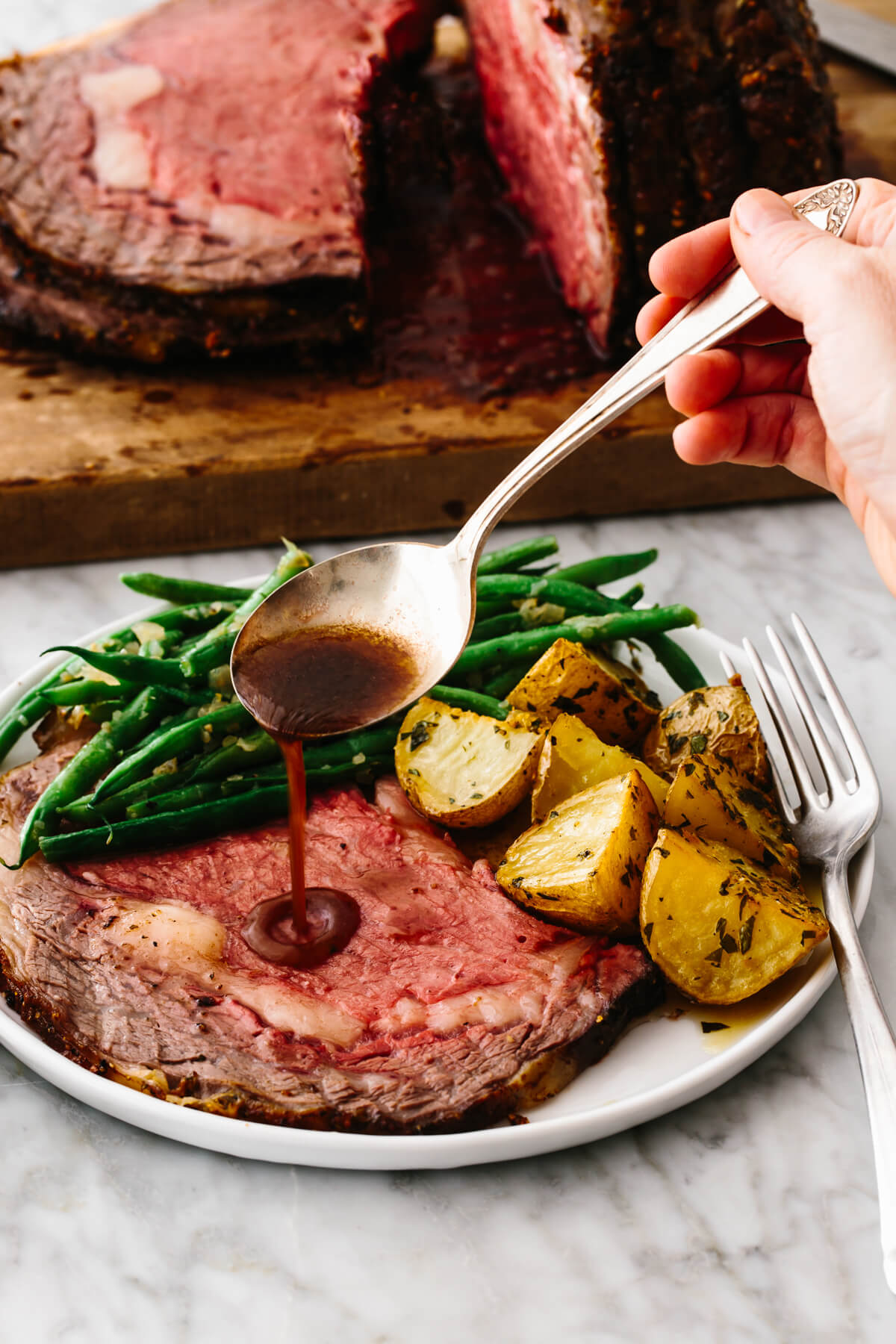 Drizzling red wine au jus over a slice of prime rib.