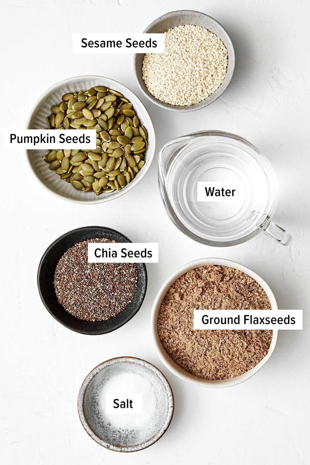 Crunchy, flavorful, and full of nutrients, these healthy seed crackers will soon be your favorite snack. Plus, they’re naturally gluten-free! Ingredients for seed crackers on a table.