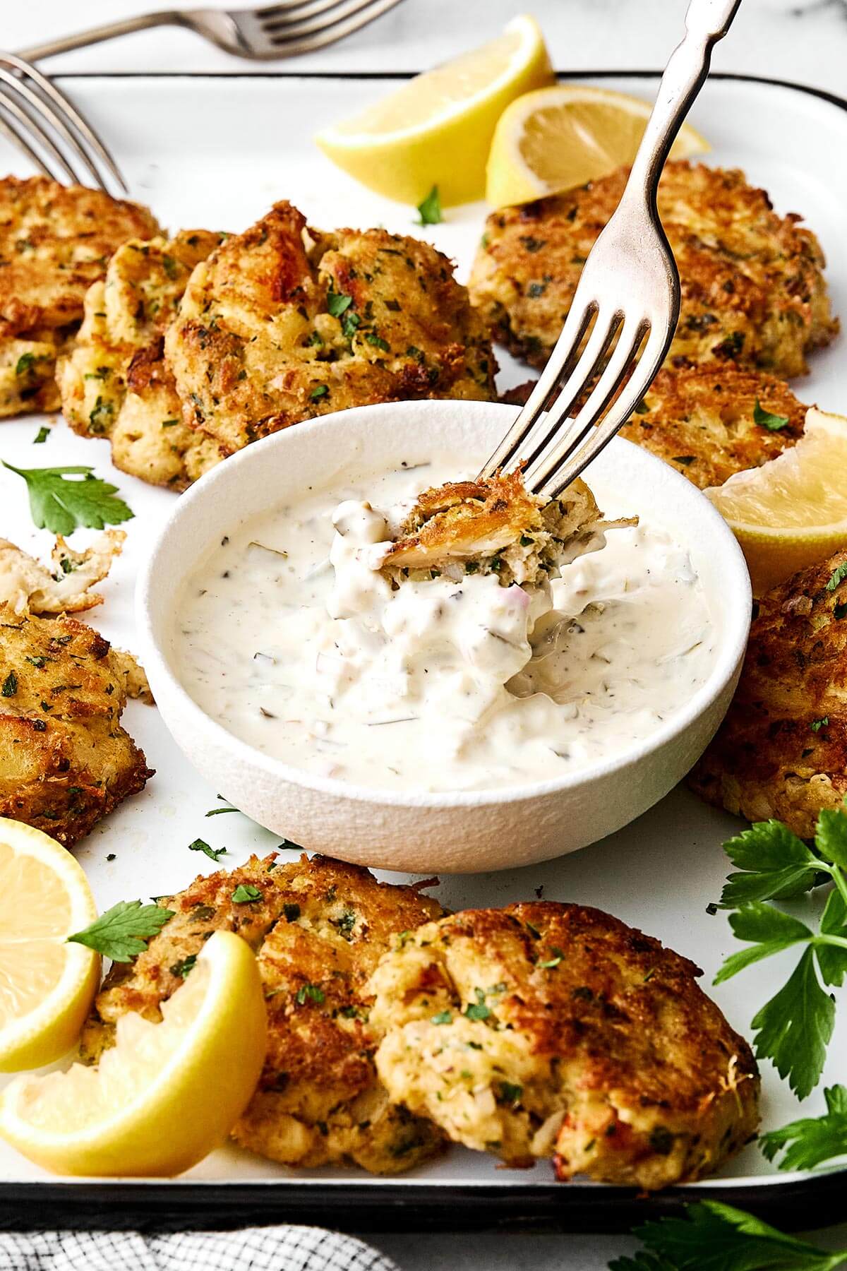Dipping crab cakes into tartar sauce.